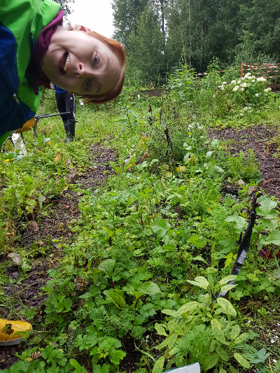 Espoon mielenterveysyhdistys Emy ry:n Kauklahden puutarhalla ihminen kurkistaa iloisena kasvimaalla